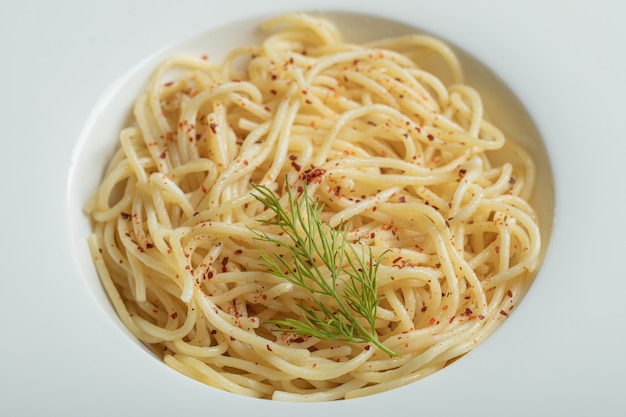 Délicieux spaghettis aux verts sur une assiette blanche.