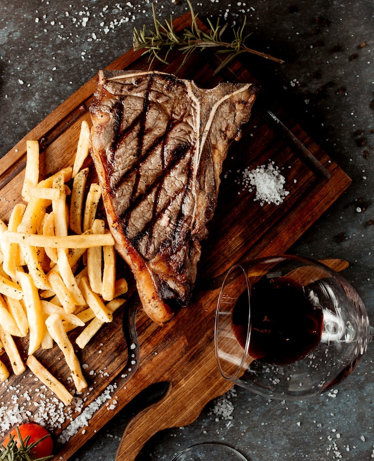 Photo gratuit délicieux steak frais avec frites sur planche de bois