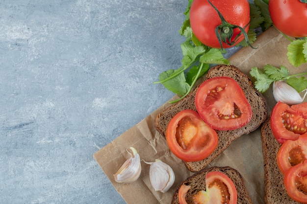 De délicieux toasts avec des tranches de tomate sur fond gris.