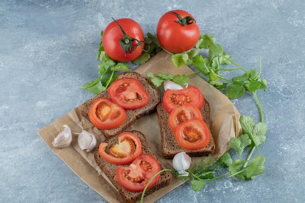 De délicieux toasts avec des tranches de tomate sur une surface grise.
