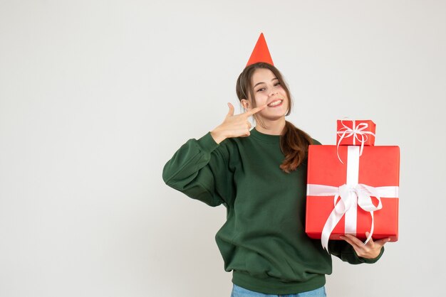 demandée fille avec chapeau de fête tenant des cadeaux pointant sur son sourire sur blanc