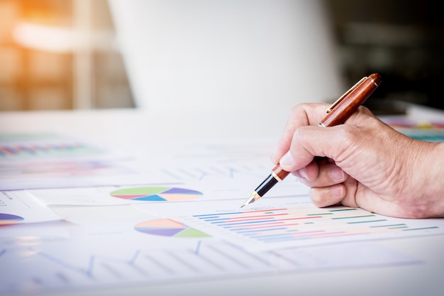 Démarrage du processus de travail. Homme d'affaires travaillant à la table en bois avec un nouveau projet de financement. Bloc-notes moderne sur la table. Stylo tenant la main