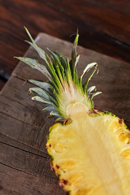 Un demi-ananas sain et juteux présenté sur une planche de cuisine sur une table en bois Ingrédient pour le dessert ou la salade Vue de dessus