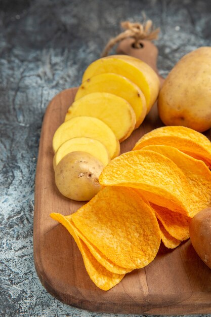 Demi-coup de chips croustillantes et pommes de terre non cuites sur une planche à découper en bois sur des images de table grise