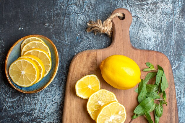 Demi-coup de citrons frais et couteau à la menthe sur une planche à découper en bois sur fond sombre