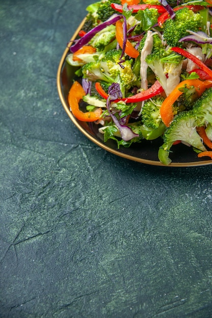 Photo gratuite demi-coup de délicieuse salade végétalienne dans une assiette avec divers légumes sur fond sombre