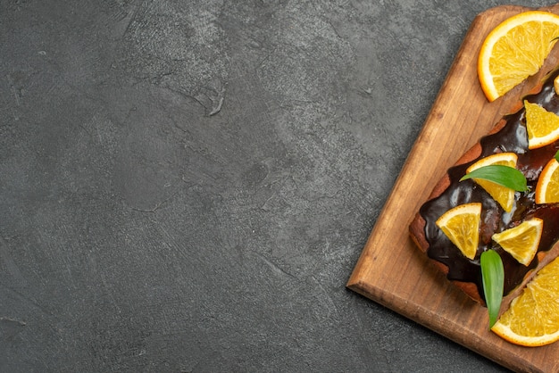 Demi-coup de délicieux gâteaux décorés de citron et de chocolat sur une planche à découper sur tableau noir