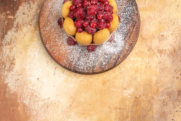 Photo gratuite demi-coup de gâteau moelleux fait maison avec des fruits sur une planche à découper en bois sur table de couleurs mixtes