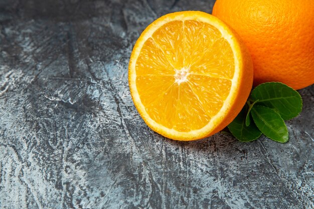 Demi-coup d'oranges entières et coupées en deux sur fond gris