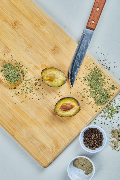 Demi-coupe mûre de prune sur une planche de bois avec des épices