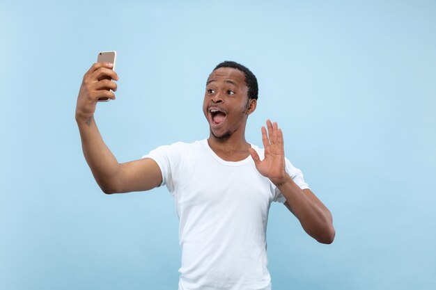 Demi-longueur gros plan portrait de jeune homme afro-américain en chemise blanche sur l'espace bleu