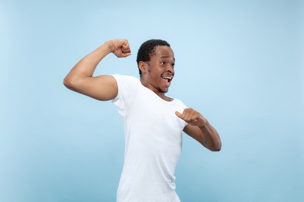 Demi-longueur gros plan portrait de jeune homme afro-américain en chemise blanche sur l'espace bleu