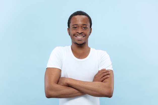 Demi-longueur gros plan portrait de jeune homme afro-américain en chemise blanche sur l'espace bleu