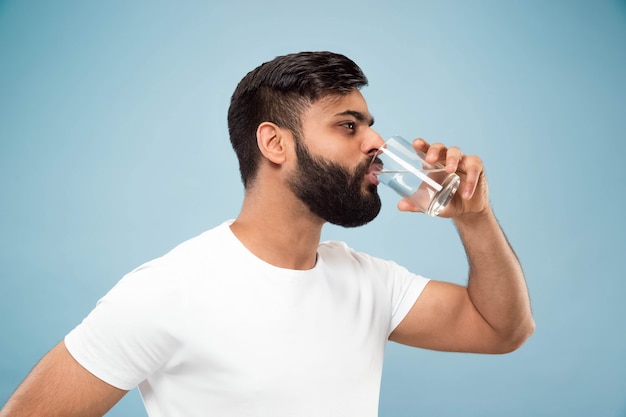 Demi-longueur gros plan portrait de jeune homme en chemise blanche sur bleu