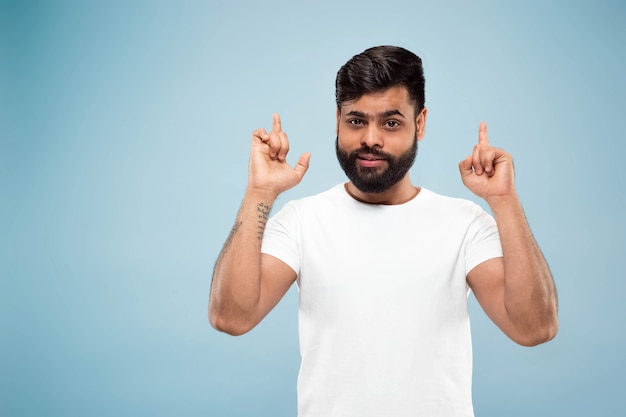 Demi-longueur gros plan portrait de jeune homme en chemise blanche sur bleu