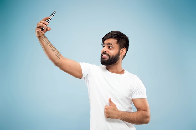 Demi-longueur gros plan portrait de jeune homme hindou en chemise blanche sur l'espace bleu