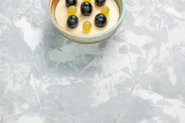 Demi-vue de dessus délicieux dessert crémeux avec des fruits sur le dessus à l'intérieur du petit pot sur une surface blanche