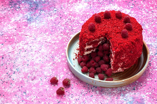 Photo gratuite demi-vue de dessus gâteau aux framboises rouges cuit délicieux à l'intérieur de la plaque sur le bureau rose.