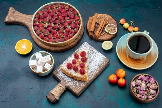 Demi-vue de dessus morceau de gâteau sucré cuit au four avec des framboises et du thé sur un bureau noir berry cake pie bake biscuit