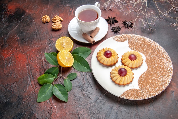 Demi-vue de dessus petits biscuits avec tasse de thé sur la table noire gâteau biscuit au sucre sucré