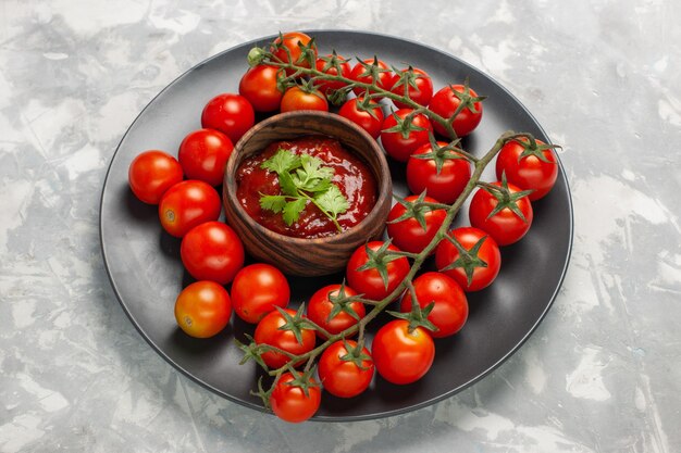 Demi-vue de dessus tomates cerises fraîches à l'intérieur de la plaque sur la surface blanche