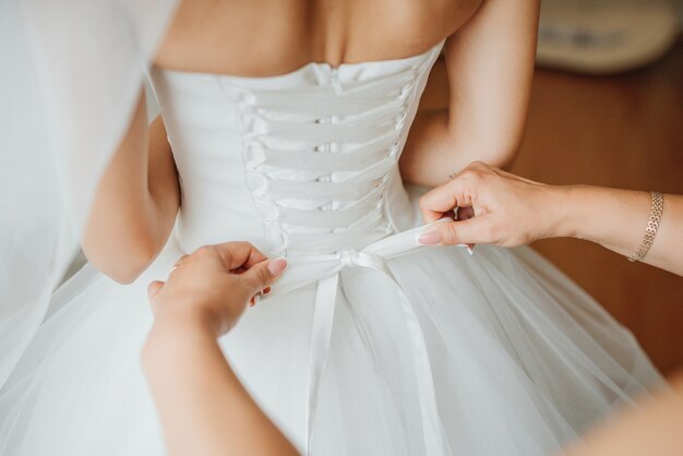 Demoiselle d&#39;honneur fait noeud noeud sur le dos de la robe de mariée de mariées