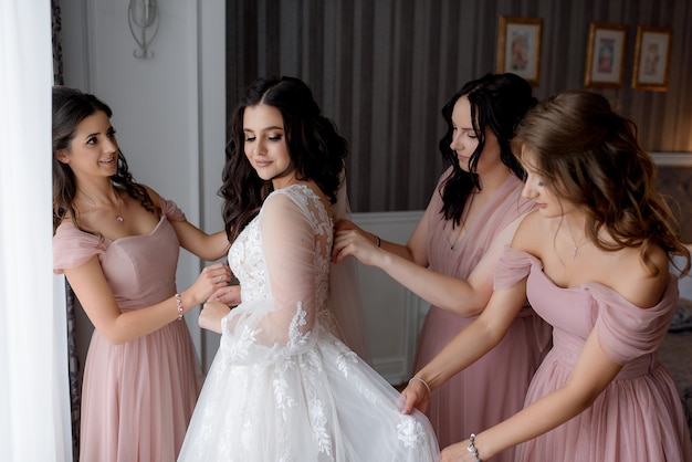 Les demoiselles d'honneur vêtues de robes roses aident la mariée à se préparer pour la cérémonie de mariage