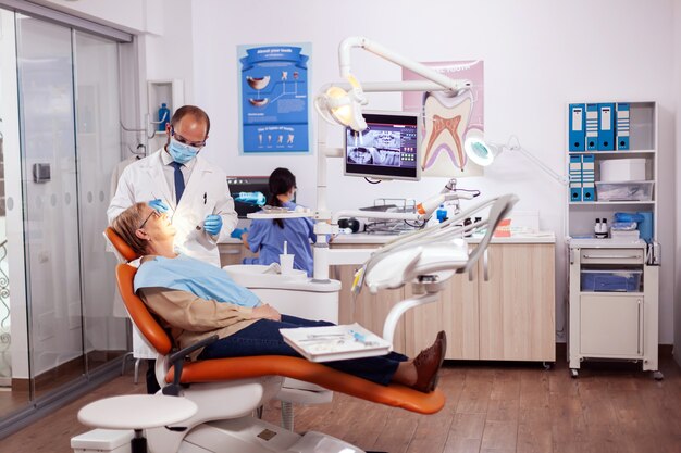 Dentiste faisant un traitement et une intervention dentaires. sur une femme âgée. Patient âgé lors d'un examen médical avec un dentiste dans un cabinet dentaire avec un équipement orange.