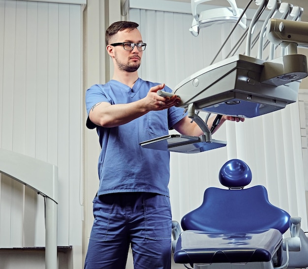 Photo gratuite dentiste masculin dans une pièce avec équipement médical en arrière-plan.