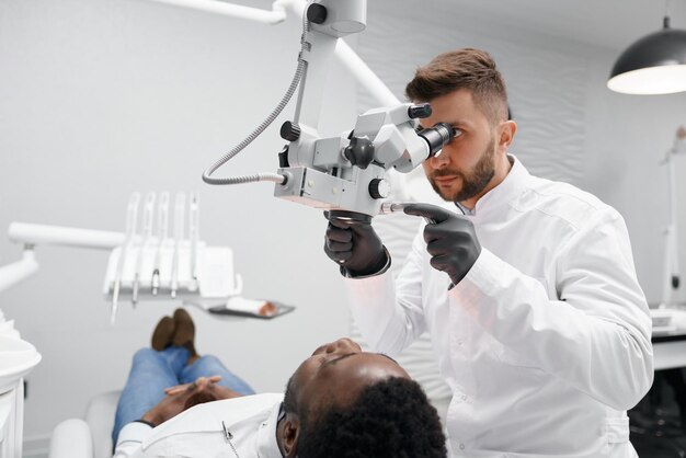 Dentiste masculin examinant les dents d'un patient masculin en clinique