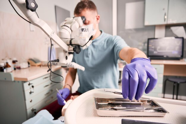 Dentiste masculin saisissant l'explorateur dentaire pendant la procédure dentaire