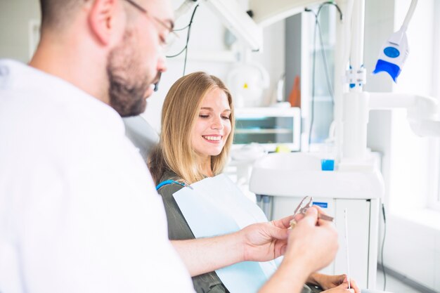 Dentiste mesurant le modèle de dents en plastique avec un pied à coulisse près d&#39;une patiente