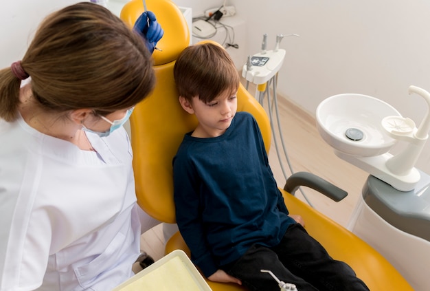 Dentiste nettoyant les dents de l'enfant