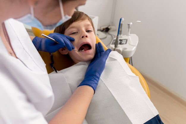 Dentiste nettoyant les dents de l'enfant