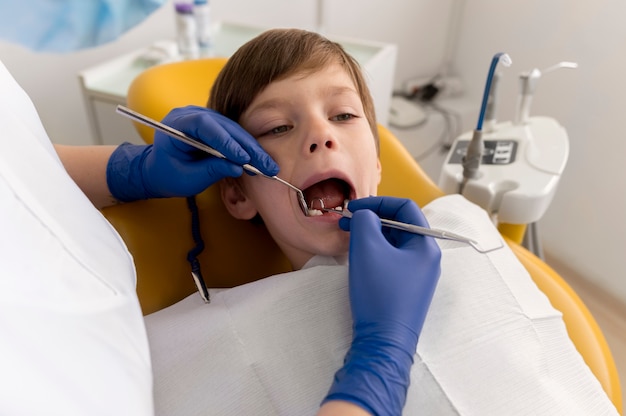 Dentiste nettoyant les dents de l'enfant