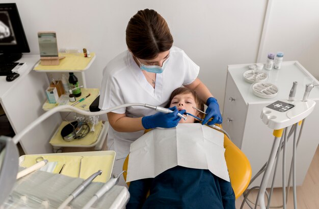 Dentiste nettoyant les dents de l'enfant