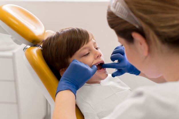 Dentiste nettoyant les dents de l'enfant