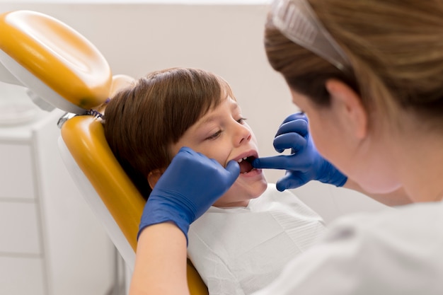 Dentiste nettoyant les dents de l'enfant