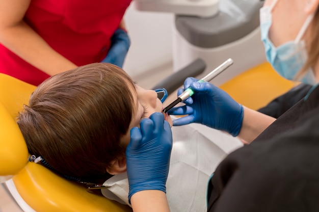 Dentiste nettoyant les dents de l'enfant