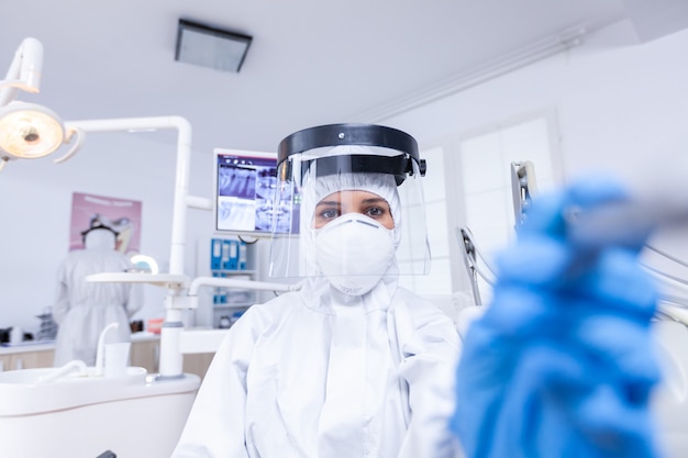 Dentiste pov vérifiant l'hygiène des dents du patient à l'aide d'une perceuse pour réparer la cavité dentaire. Stomatolog portant un équipement de sécurité contre le coronavirus lors du contrôle des soins de santé du patient.