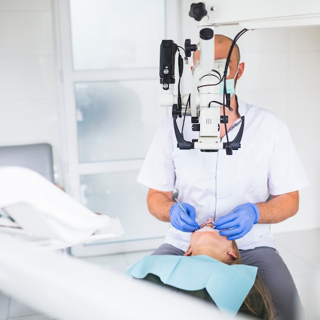 Dentiste professionnel examinant le patient avec un microscope dentaire