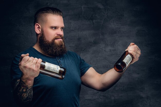 Dépendance à l'alcool. Homme barbu regardant deux bouteilles de bière vides.