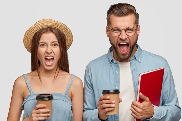 Désespéré, beau couple posant contre le mur blanc