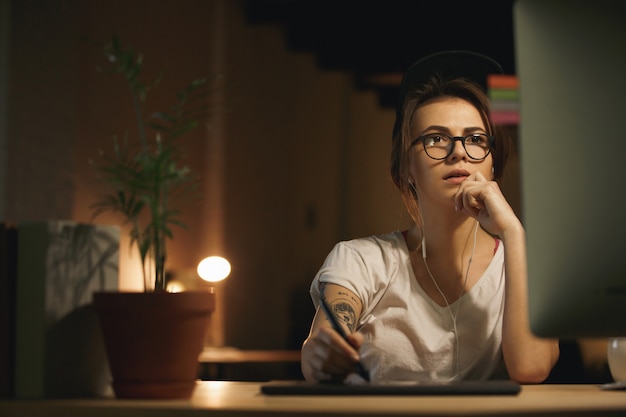 Designer femme sérieuse à l'aide d'une tablette graphique et d'un ordinateur