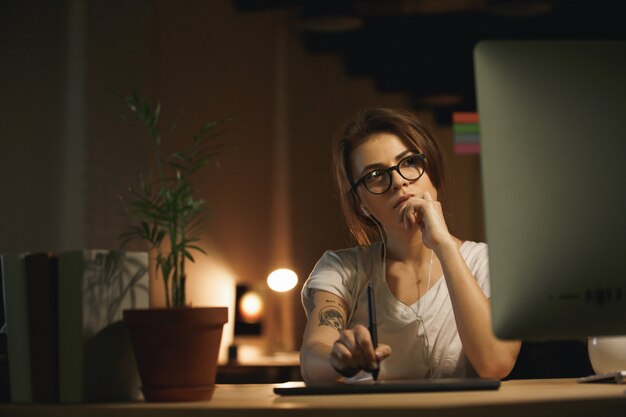 Designer femme sérieuse à l'aide d'une tablette graphique et d'un ordinateur