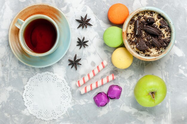 Dessert de biscuit au chocolat vue de dessus avec des bonbons de macarons français et du thé sur un biscuit de bureau blanc clair