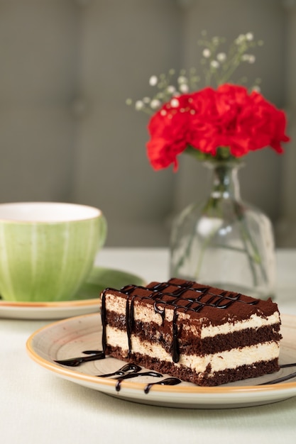 Dessert de gâteau au chocolat avec vase à fleurs et tasse floue