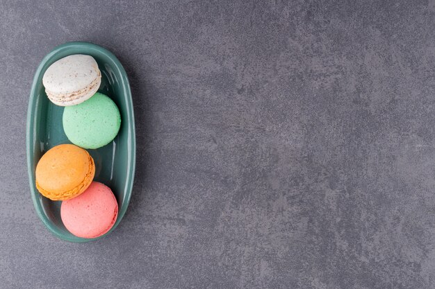 Dessert macarons colorés placés sur une table en pierre.