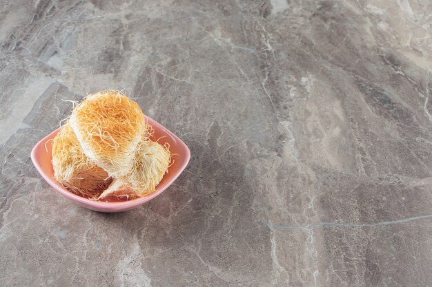 Dessert turc kadayif dans un bol sur marbre.