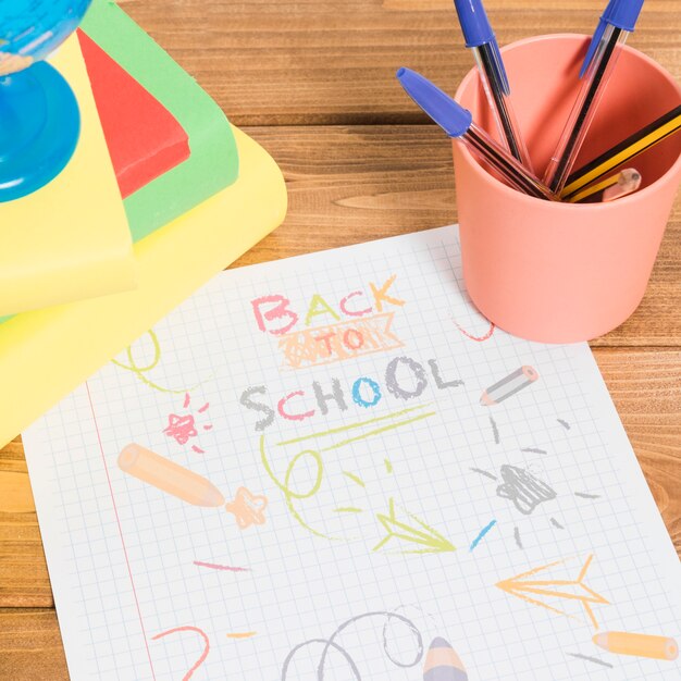 Dessin de couleurs sur papier à l'école sur une table en bois avec des livres et des crayons